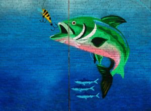 A painting of a fish about to swallow bait on a hook.