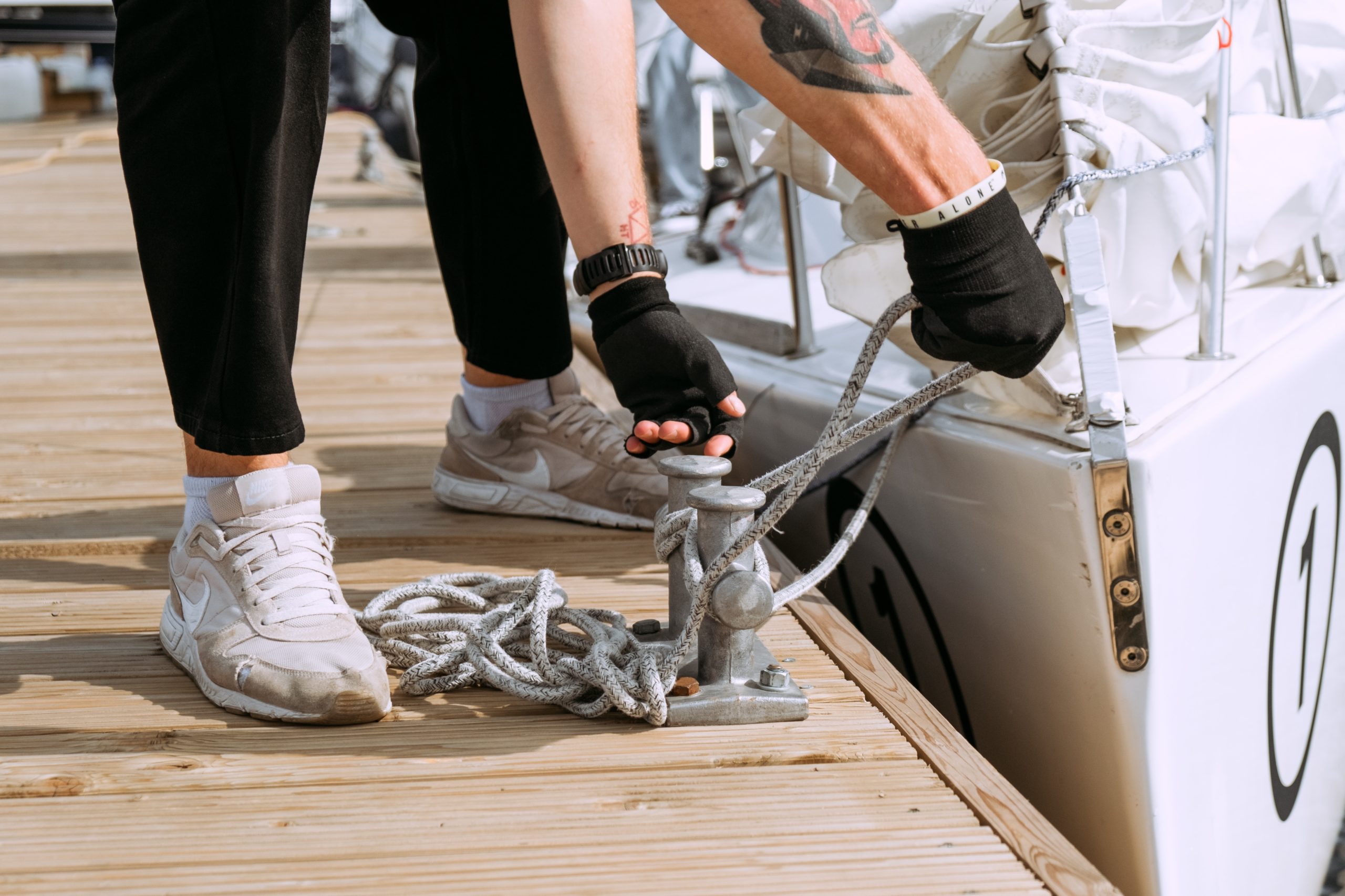 Hands tying up a boat to a dock.