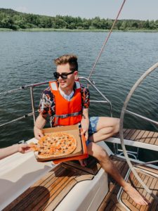 Man with a pizza on a boat.