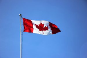 The Canadian flag waving against a blue sky.
