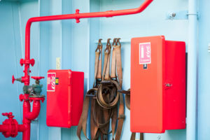Boat fire extinguisher with red cabinet against blue walls.